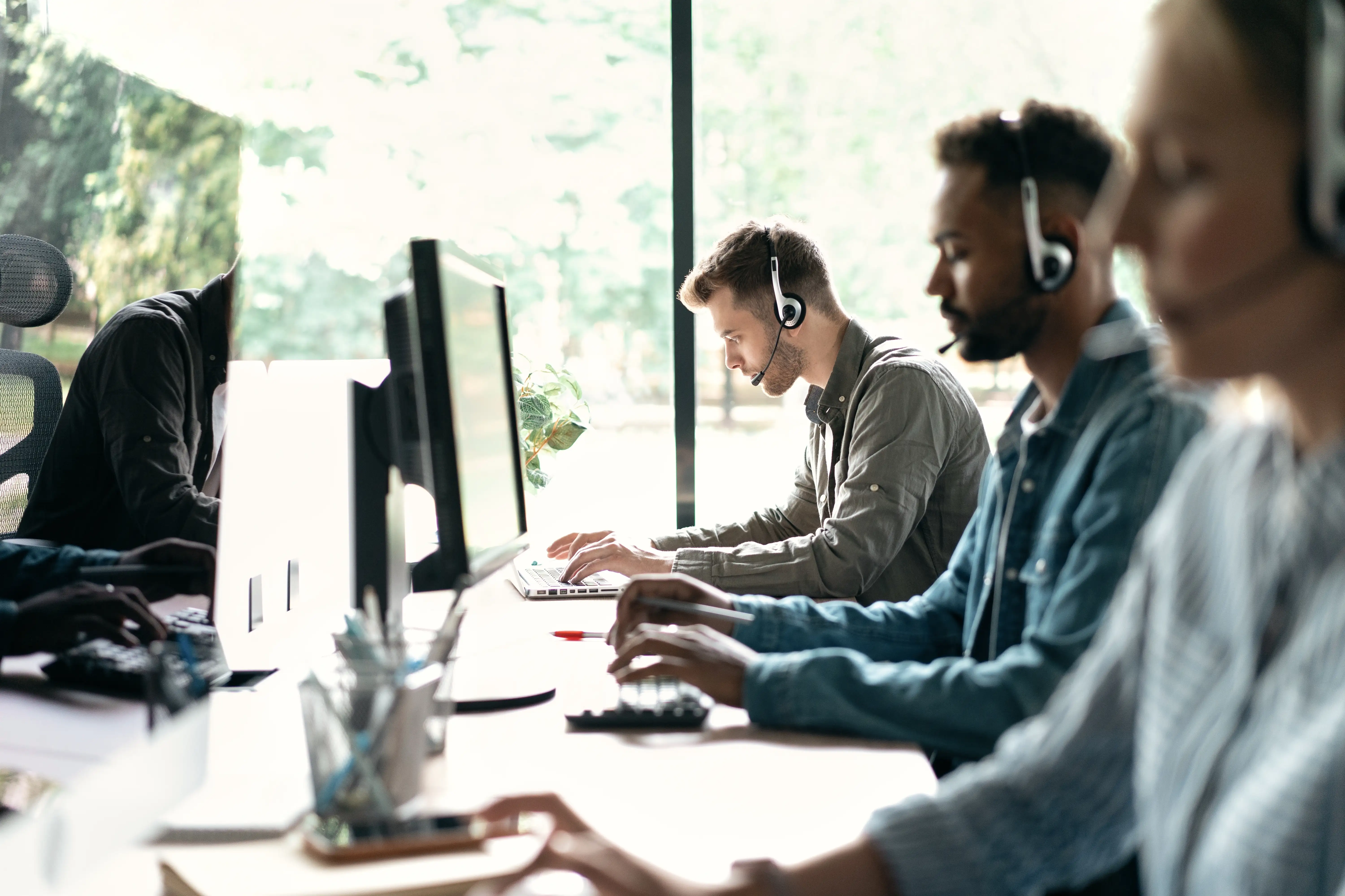 Two males one female working with headsets on
